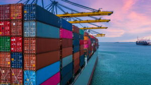 Cargo ship with huge stacks of containers docking at a port of call
