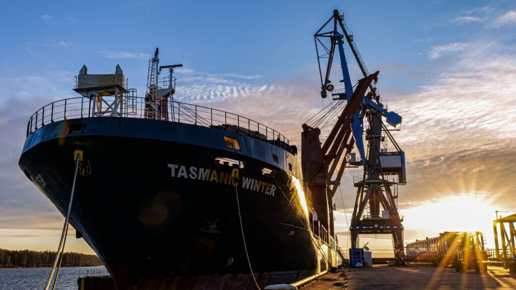 Ship docked at a port of call alongside a crane to unload containers