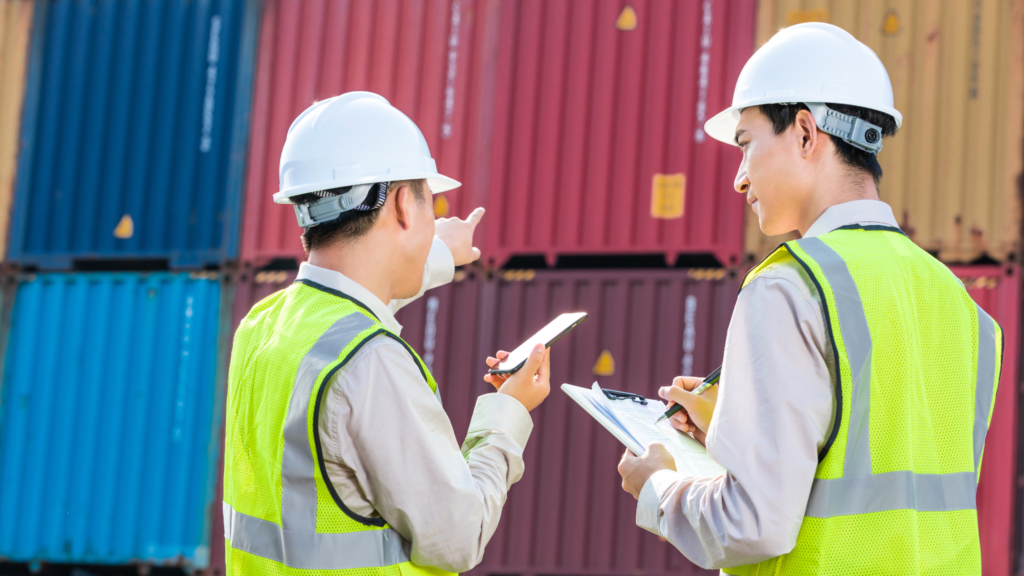 Port workers in green checking on containers