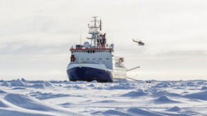 A research ship with a helicopter flying above