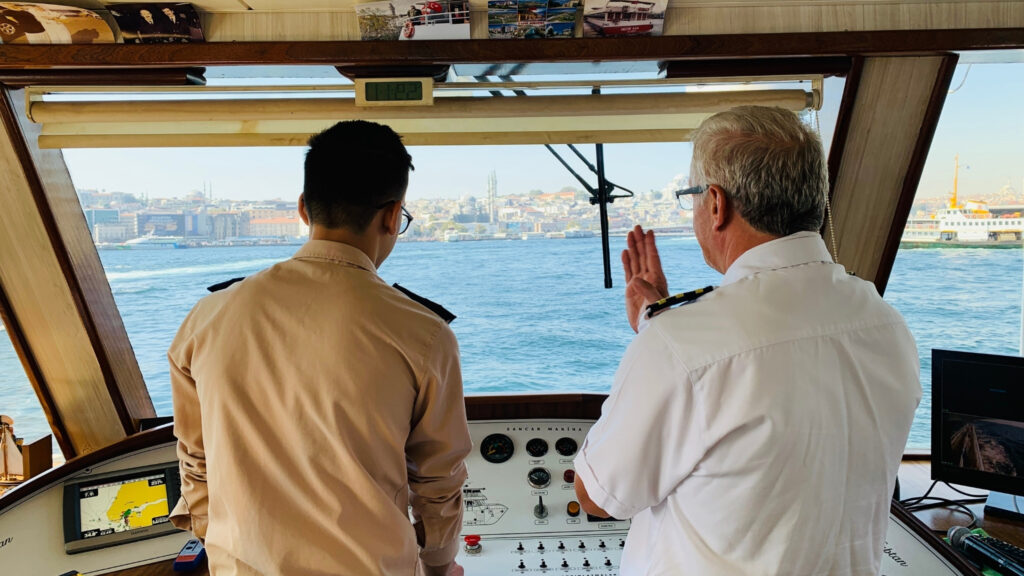 Two officers at the bridge steering the ship into a port