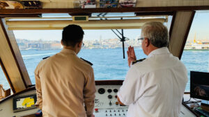 Two officers at the bridge steering the ship into a port