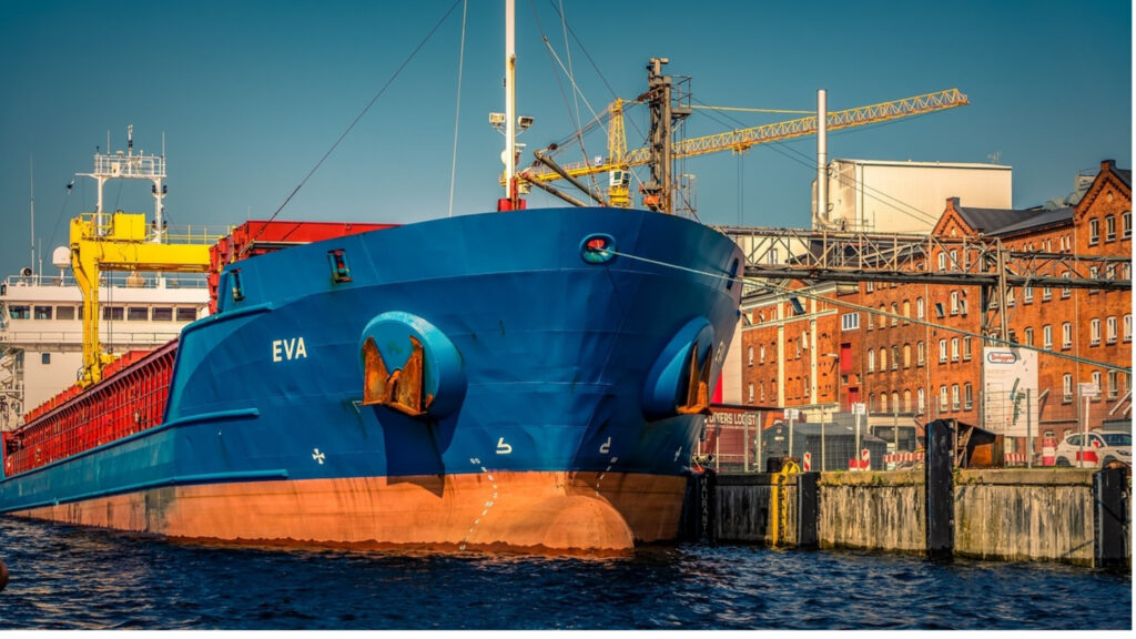 Cargo ships docked at a port of call with cranes unloading containers
