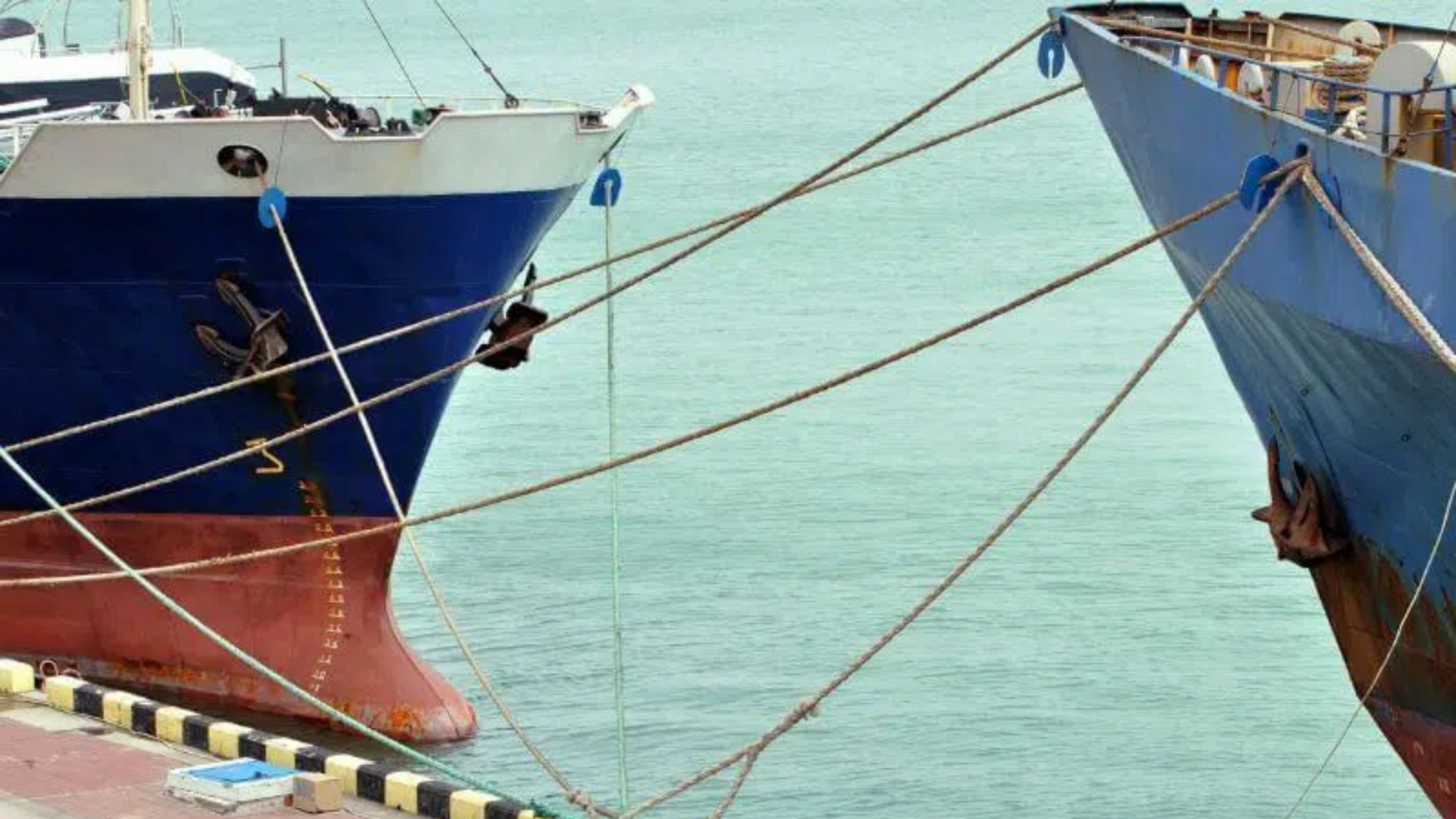 Two ships tied together and docked at a port of call