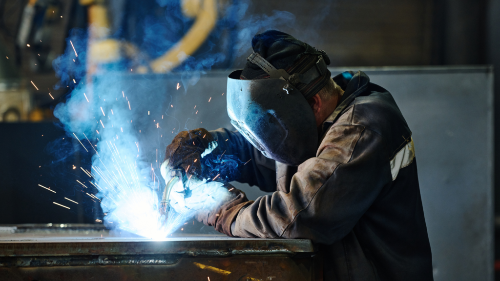 A Worker in a Mask performing welding work on a workbench