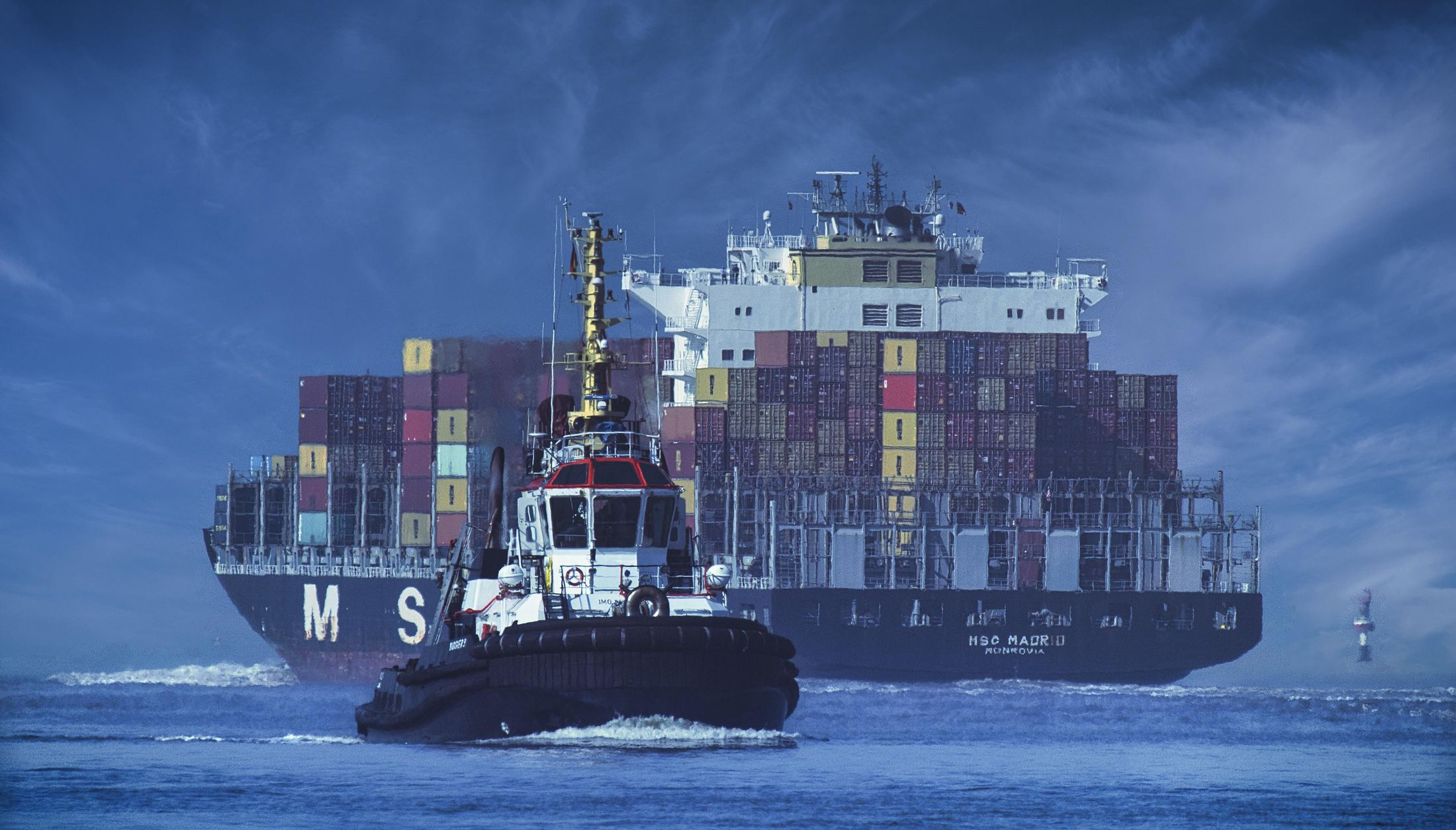 A container ship under tug escort at sea