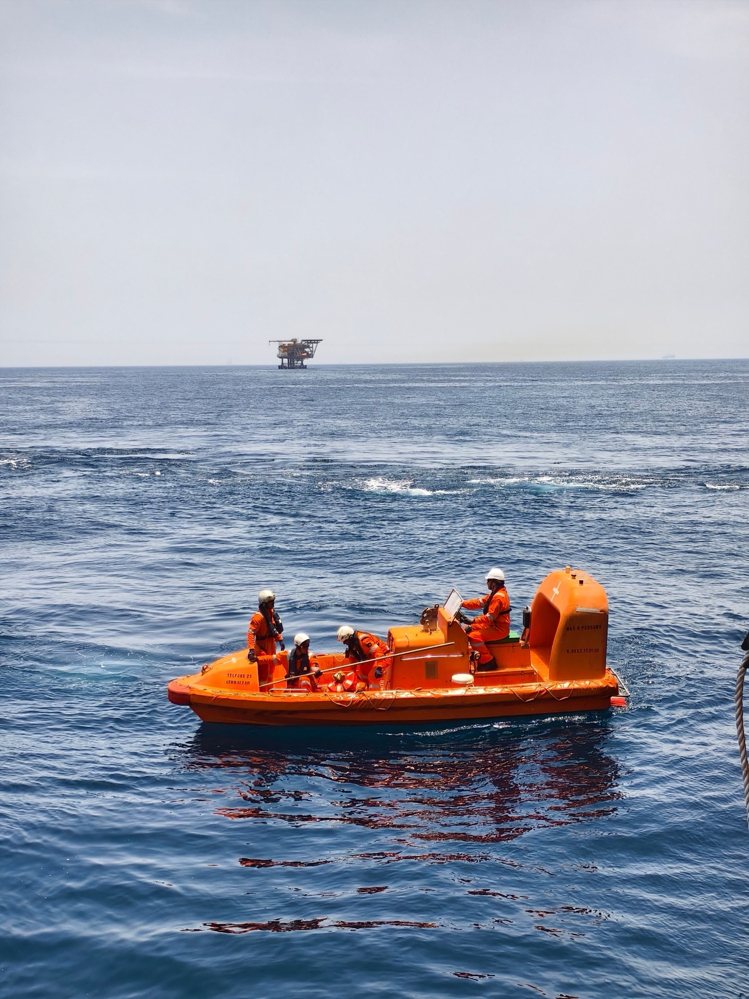 Lifeboat at sea beside a platform