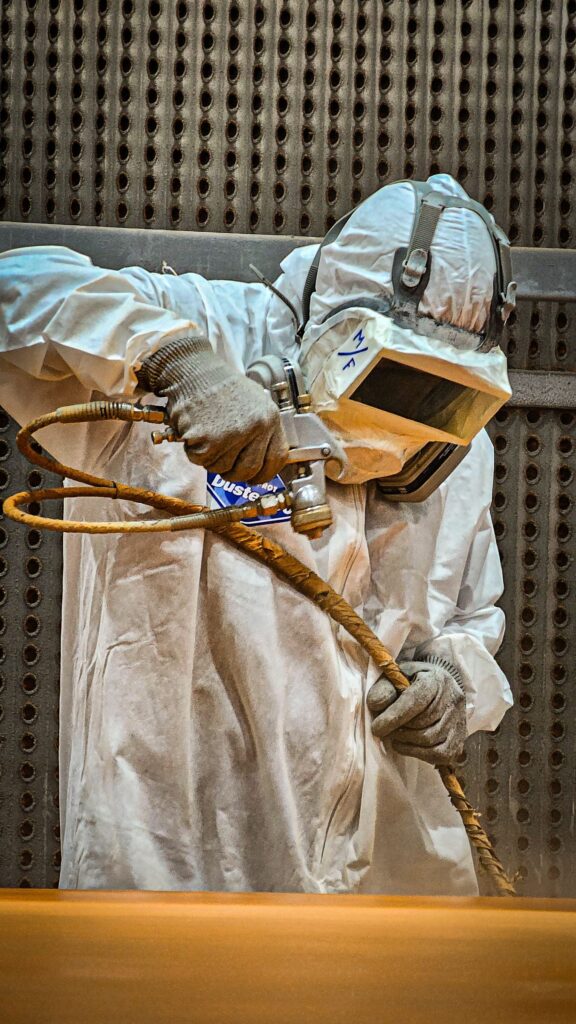 Close work applying a coat to steelwork in protective suit and respirator