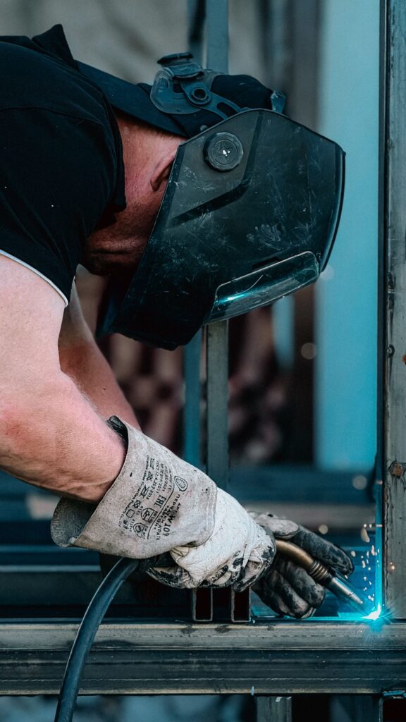 Close view of gloved hands welding a steel section