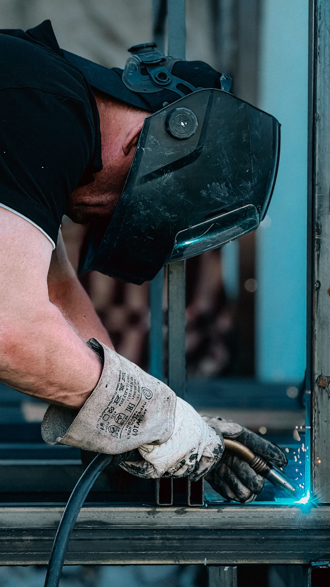 Close view of gloved hands welding a steel section